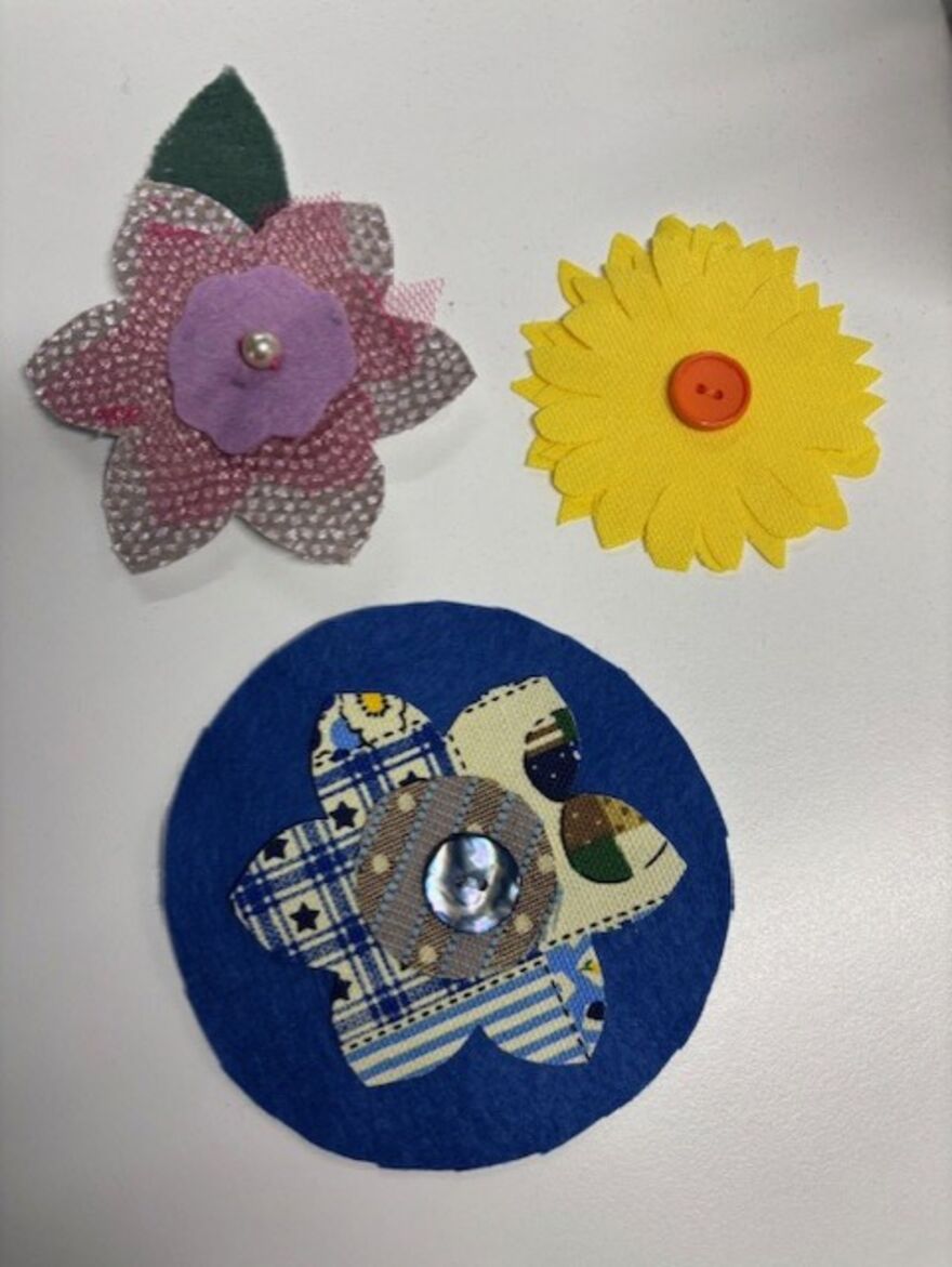 From left to right: Three nature inspired brooches, including flowers, made using recycled textiles.