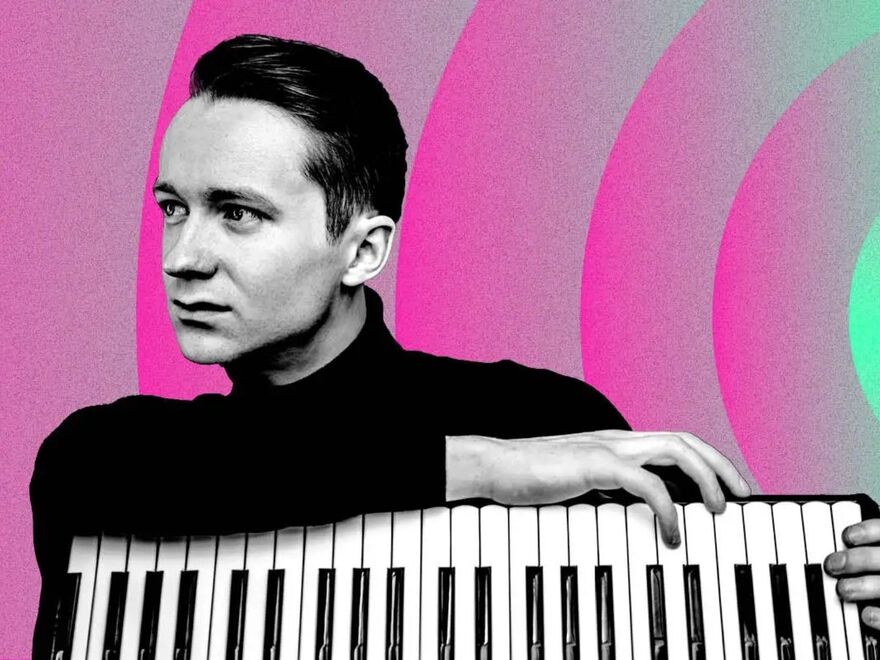 A black and white photo of accordion player Ryan Corbett on a pink and green background.