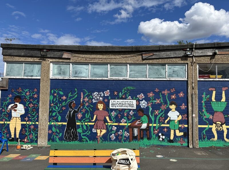 Mural with children playing on dark blue background surrounded by flowers at Brandlehow School.