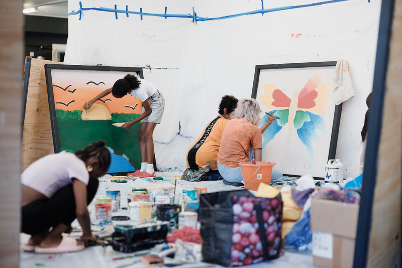 A co-production workshop where four figures are painting the 9 Ram St Mural panels (photo credit Nahwand Jaff)