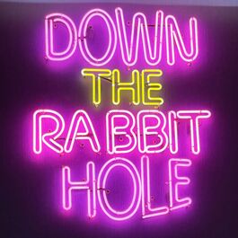 a purple and yellow neon sign saying Down the Rabbit Hole
