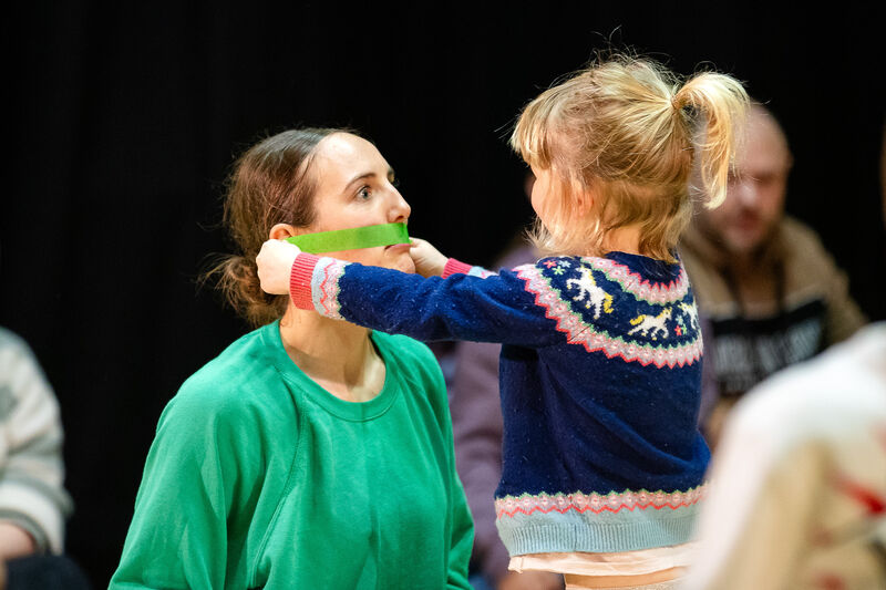 A young girl is putting tape across one of the dancer's mouths 