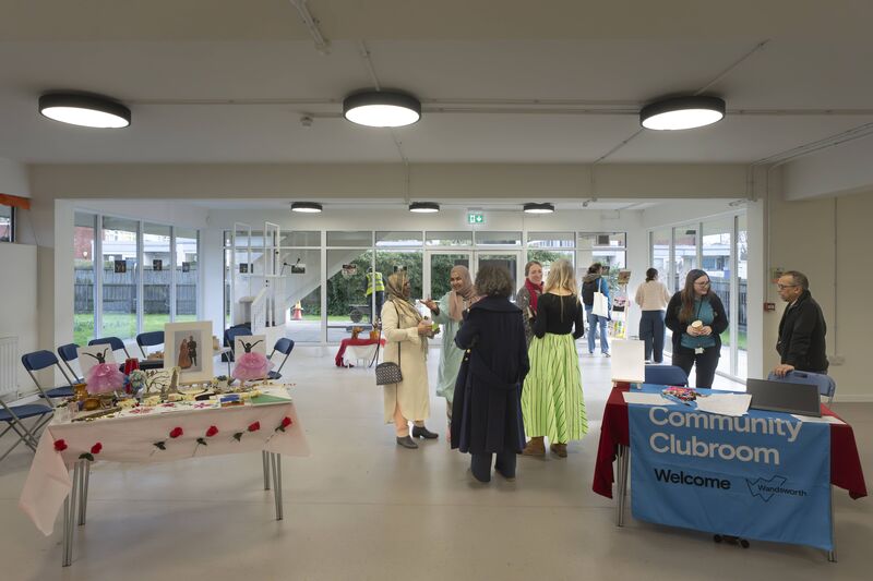 Community gathering in the downstairs room of Focus Hall with a welcome table, and some artworks laid out