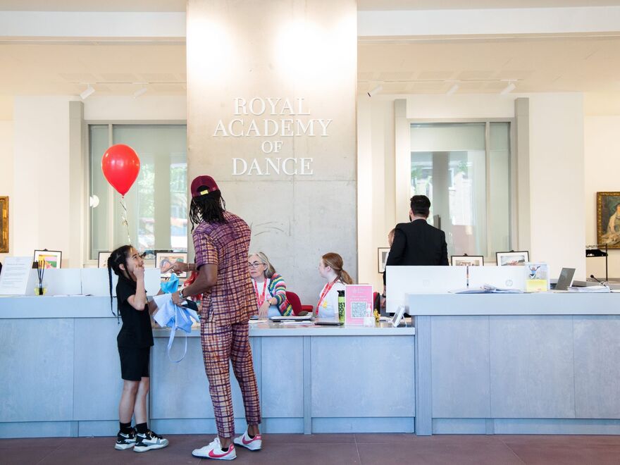 A picture of a child holding a balloon and adult in the reception of the Royal Academy of Dance