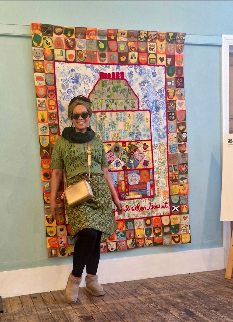 Fée Uhssi in front of the Community Quilt as part of National Trust's 575 Wandsworth road Common Thread project where Fée led the appliqué design part.