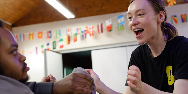 BLINK facilitator Connie smiles broadly at a workshop participant, holding their hand.