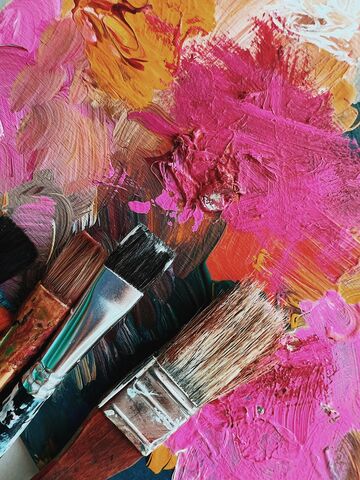 Pink and yellow brushstrokes with paintbrushes in the bottom left corner.