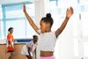 little girl blows a bubble with her arms in the air