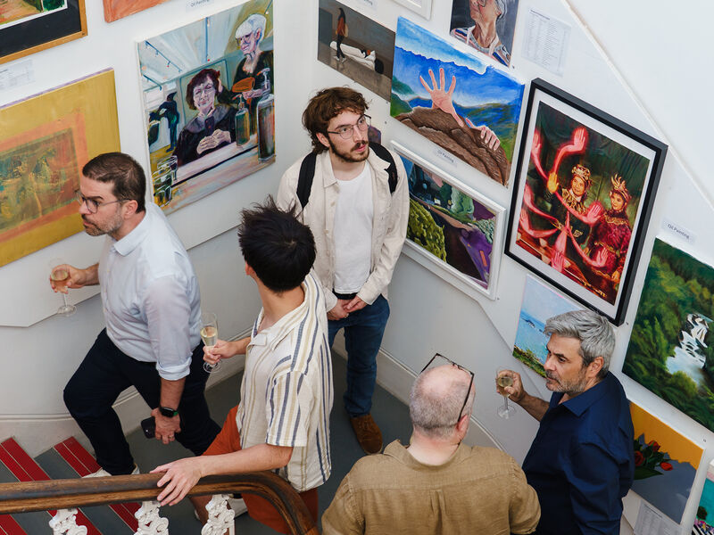 Exhibition visitors on a staircase looking at artwork