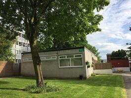 green space with gre building in middle left with big tree