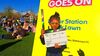 a young girl in facepaint holds a clapperboard in front of a sunny lawn full of people