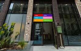 red blue purple pink green and orange sign dark grey building with darkened windows