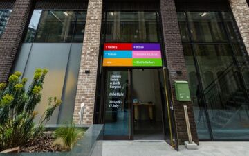 red blue purple pink green and orange sign dark grey building with darkened windows