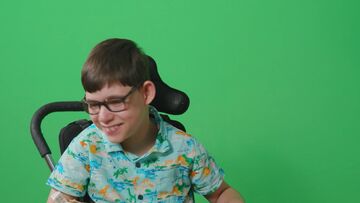 Child in wheelchair in front of green screen