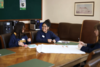Some young people working around a wooden table on a large sheet of paper
