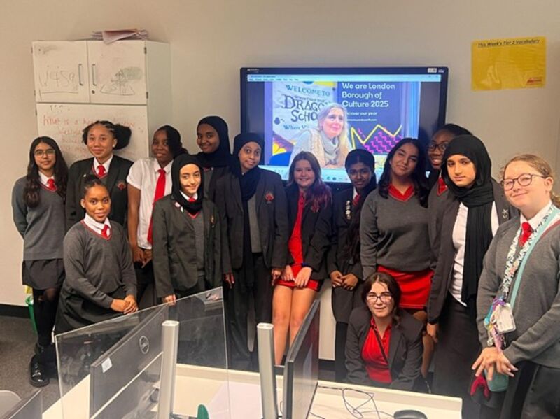 Group of school children sitting in front of white board with woman on screen