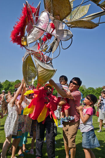 A group of children and adults hold up a lantern sculpture. 