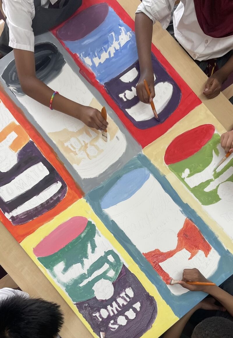 Children's hands painting a variation of Andy Warhol's soup cans at Chesterton School.