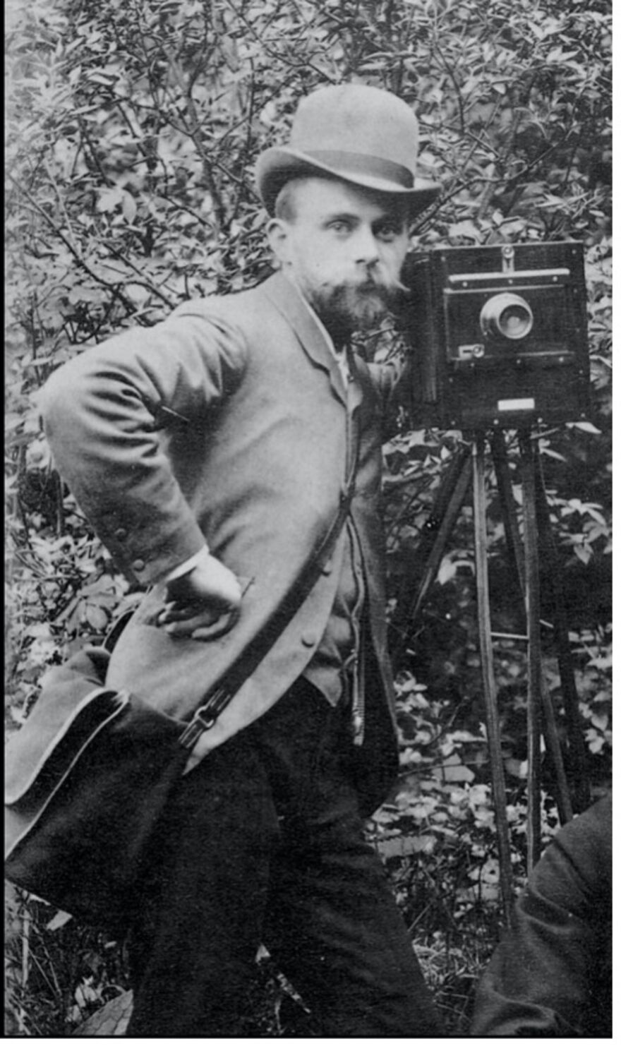 Image of Paul Martin posing alongside camera. He has a beard and moustache and is wearing a jacket with his hand on his hip