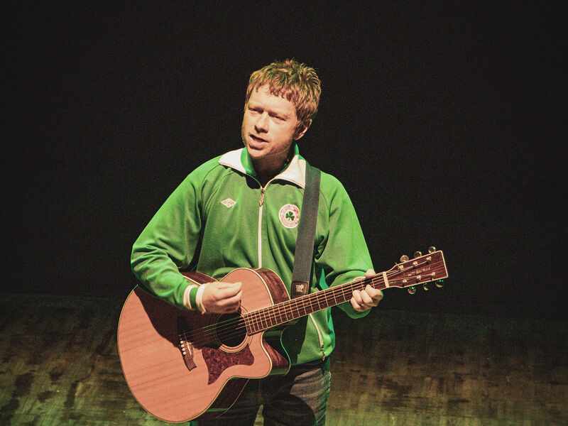 Photo of Declan Duffy on stage with guitar and singing
