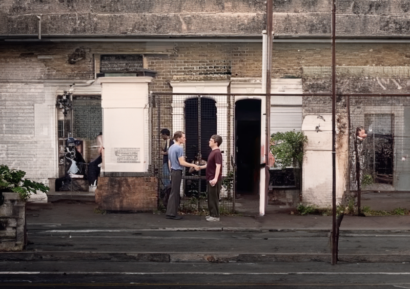Two people shaking hands. Next to a house. 
