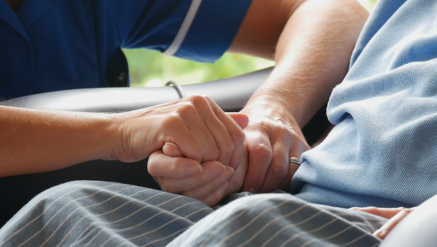 Two hands holding a hand supportively. 