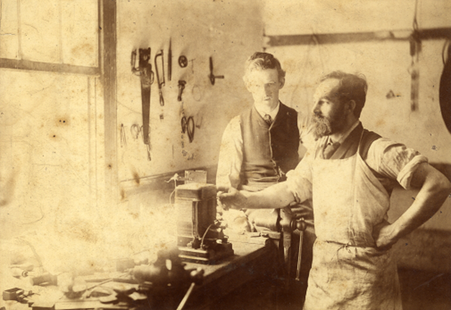 Photographic showing John Burns operating a vice in a workshop. Wandsworth Libraries & Heritage Service