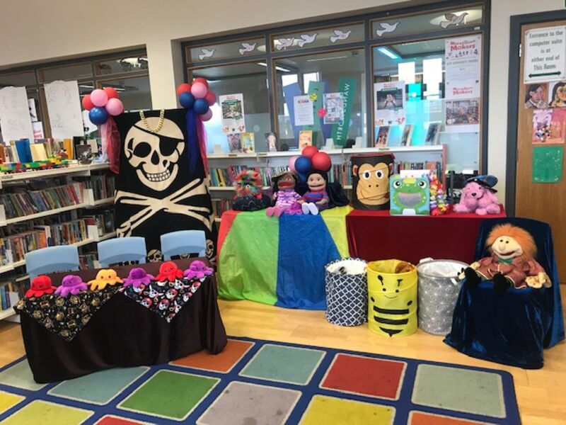 Stage set up for the drama and storytelling with puppets and  resources. Photo shows puppets, colourful cloths and boxes of props and a giant pirate cloth.