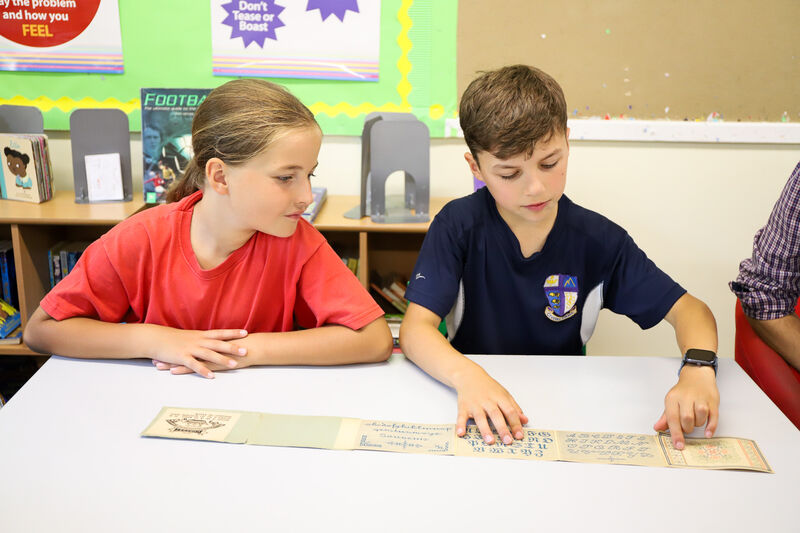 Two children at a table looking at a piece of paper