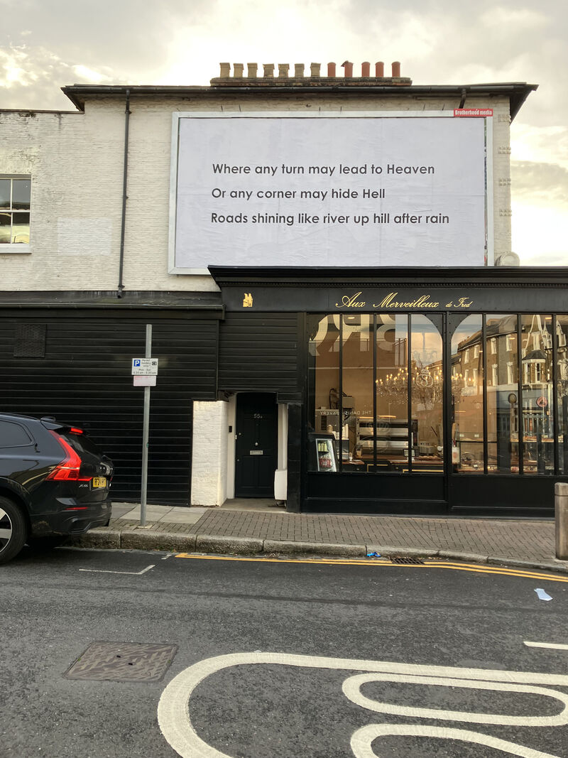 An image of a text installation on a billboard in Shelgate Road, reading 'Where any turn may lead to Heaven, Or any corner may hide Hell, Roads shining like river up hill after rain'